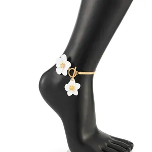 Detail shot of golden snake chain anklet with white floral charms and OT buckle