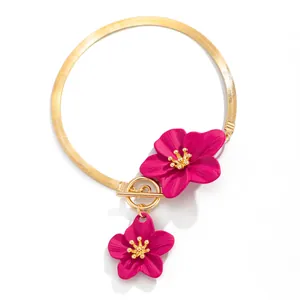 Detail of golden herringbone chain anklet with vibrant magenta oil-drip flower charms.