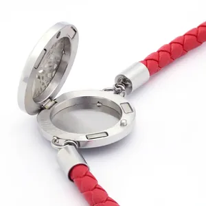 Dettaglio del medaglione diffusore di profumo aperto con bracciale in pelle intrecciata