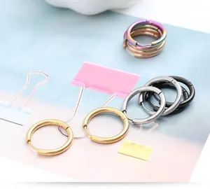 Primer plano de pendientes de aro de acero inoxidable en acabados dorado, plata y negro.