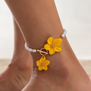 Detailed view of beach anklet with yellow flowers and white pearls on ankle.