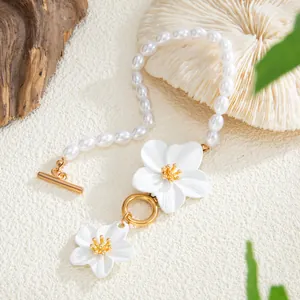 Close-up of beach vacation pearl anklet with white flower pendant and gold clasp