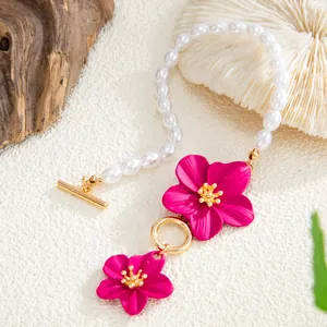 Close-up detail of vibrant pink enamel flower charms and elegant white pearls on beach anklet