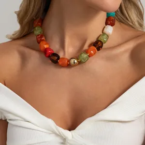 Primo piano dettagliato di una collana bohémien in resina colorata con sfera dorata.