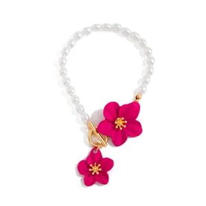 Detailed view of pink flower charms and gold OT clasp on a white pearl anklet