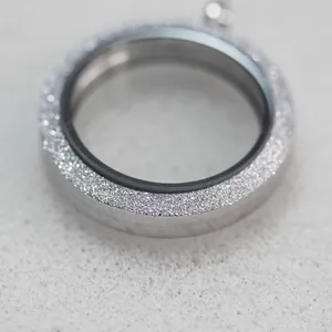 Macro view of a silver frosted stainless steel magnetic locket pendant with glass