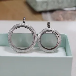 Close-up of two frosted silver locket pendants in different sizes on a gift box