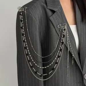 Punk style multi-layer long chain brooch with black crystals shown on a pinstripe blazer.