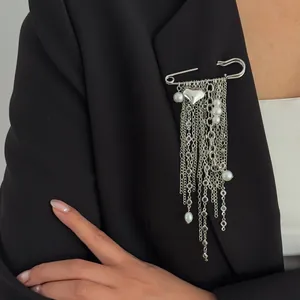 Detailed macro view of the silver heart tassel brooch with pearls pinned on a black blazer.
