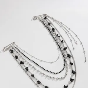 Detail of a punk style silver multi-layered chain brooch with black crystal beads