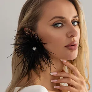 Gros plan sur d'élégantes boucles d'oreilles en plumes noires avec strass central.
