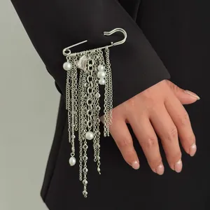 Detail of a large silver safety pin brooch with cascading pearl and heart chain tassels