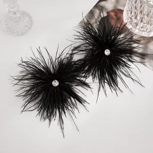 Vue détaillée de boucles d'oreilles en plumes noires avec un strass central étincelant.