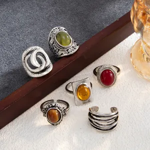 Selection of vintage silver rings with assorted colorful gemstones on a textured surface