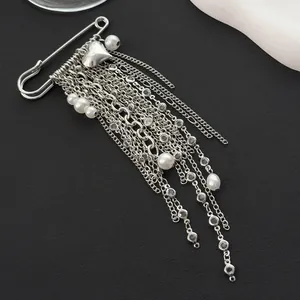 Close-up of silver tassel brooch with pearls and delicate heart chain details