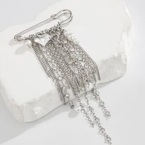 Close-up of silver heart brooch with pearl tassels and layered chains detail