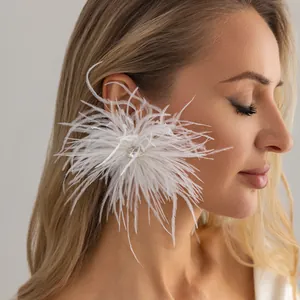Gros plan d'une boucle d'oreille en plumes blanches avec un strass étincelant au centre.