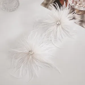 Détail de boucles d'oreilles clous en plumes blanches avec un strass central étincelant.