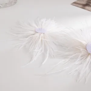Vue détaillée en gros plan de boucles d'oreilles en plumes d'autruche blanches et douces