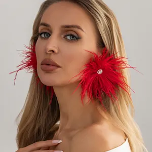 Détail de boucles d'oreilles surdimensionnées en plumes rouges avec strass sur mannequin