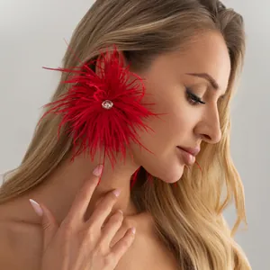 Gros plan d'un mannequin blond portant des boucles d'oreilles en plumes rouges et strass