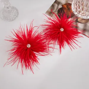 Vue détaillée de boucles d'oreilles en plumes d'autruche rouges avec strass scintillant.