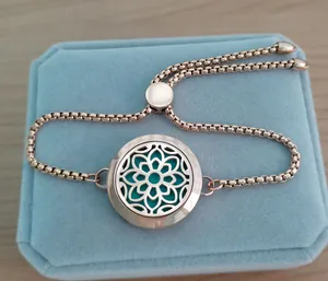 Detail view of 25mm rose gold aromatherapy bracelet with floral locket on blue box