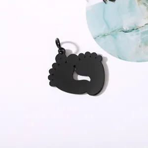 Macro view of a black mirror-polished stainless steel baby footprint charm DIY pendant