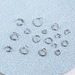 Multiple sizes of 304 stainless steel jump rings for DIY jewelry making on blue background.
