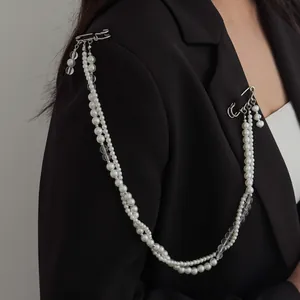 Gros plan sur une élégante broche à pompon en perles blanches et épingle à nourrice sur blazer.