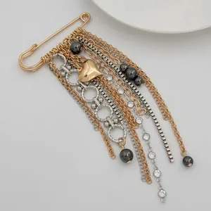 Detail shot of gold heart safety pin brooch with multi-layered tassels and metallic beads