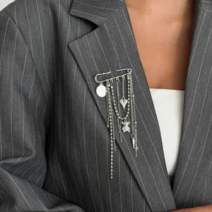 Silver safety pin brooch with heart and bear charms shown on a pinstripe blazer
