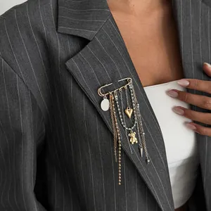 Detail of a stylish safety pin brooch with heart and bear tassels on a pinstripe blazer.