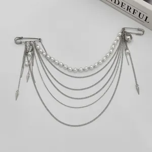 Détail de la broche à pompons en perles et chaîne argentée multicouche avec épingle