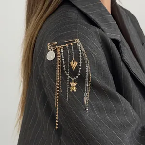Detail of fashion DIY safety pin brooch with heart bear charms and long metal tassels