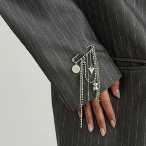 Detail view of a stylish silver bear and heart tassel brooch on a grey pinstripe suit sleeve
