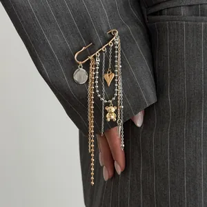 Detailed close-up showing heart and teddy bear charms on the tassel pin brooch
