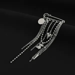 Close-up of silver-tone safety pin brooch with heart, bear charms and multi-layer bead chains