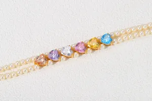 Primer plano de dijes de circón con forma de corazón en un collar de perlas de doble hilera.