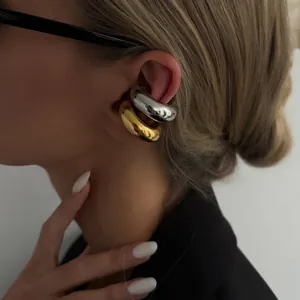 Detailed close-up of stylish gold and silver chunky C-shaped ear cuffs worn on a model