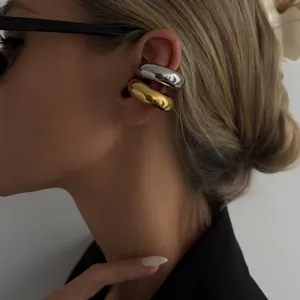 Close-up of minimalist gold and silver C-shaped stainless steel ear cuffs on a model