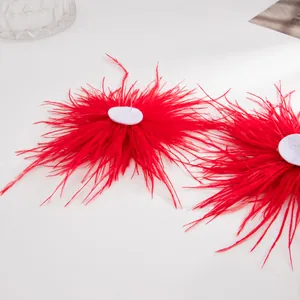 Gros plan détaillé de boucles d'oreilles en plumes d'autruche rouge vif sur fond blanc