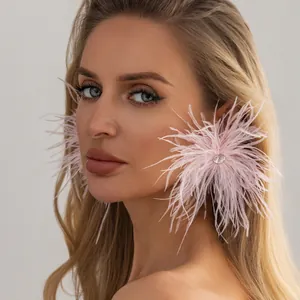 Vue détaillée de boucles d'oreilles en plumes roses avec un strass central brillant