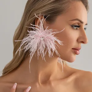 Gros plan élégant de boucles d'oreilles en plumes roses avec un centre en strass brillant