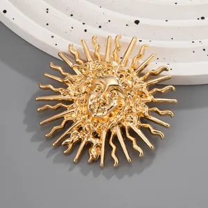 Détail d'une broche en relief déesse soleil dorée avec des rayons ondulés texturés