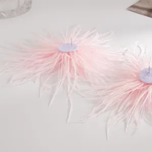 Vue détaillée de boucles d'oreilles clous en plumes roses avec une texture douce et chic