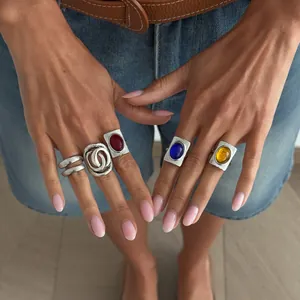 Vintage French style rings with colorful gemstones worn on hands with denim background