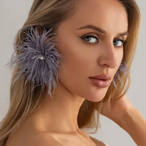Gros plan élégant de boucles d'oreilles en plumes d'autruche violettes avec strass sur mannequin