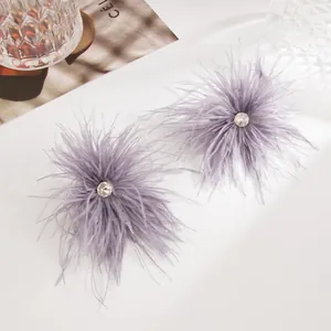 Vue rapprochée de boucles d'oreilles en plumes de lavande avec centre en strass