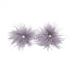 Vue détaillée de boucles d'oreilles en plumes mauves avec un strass étincelant.